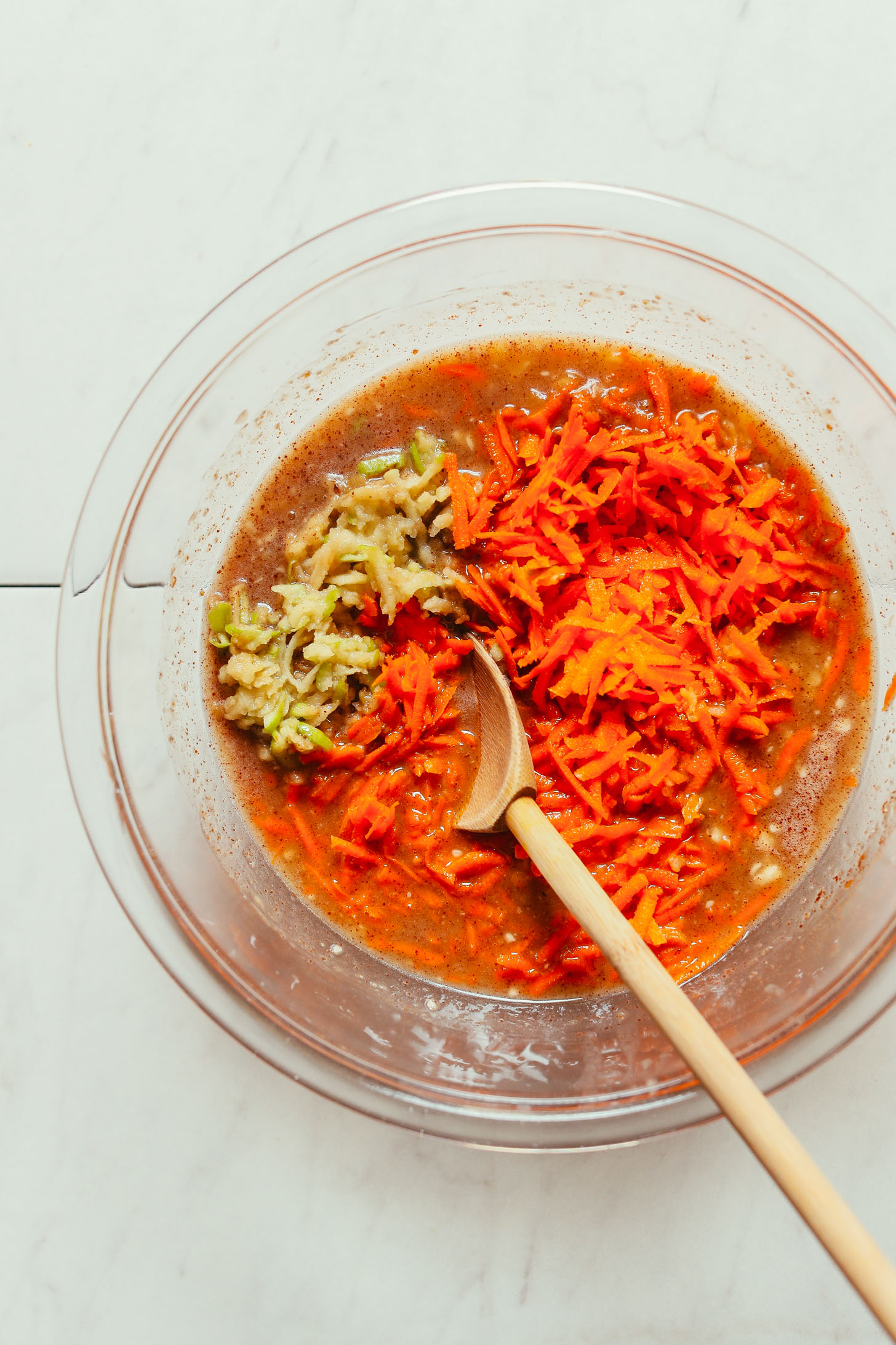 Bowl of Carrot Apple Snack Cake batter with grated apples and carrots on top