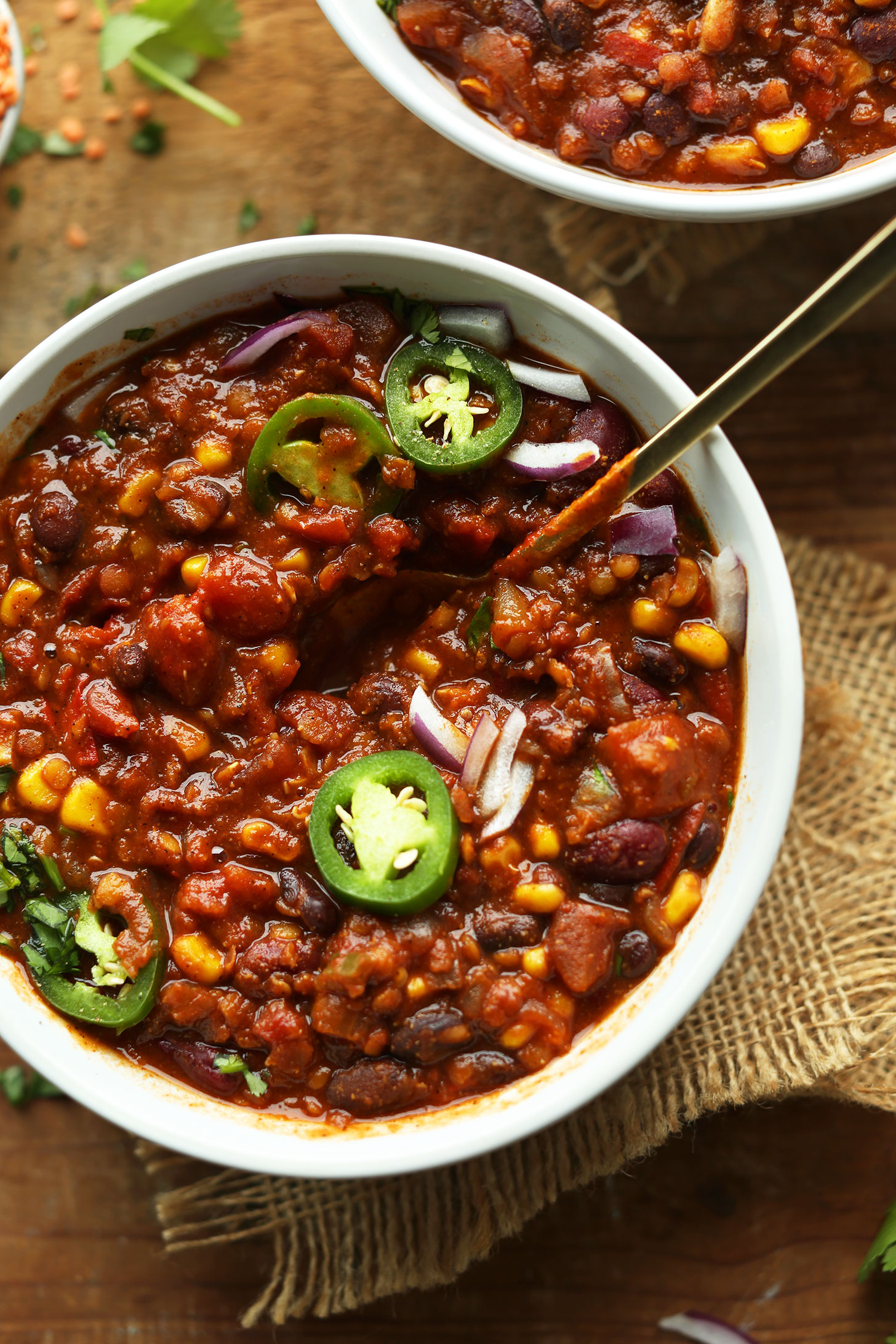 Big bowl of Red Lentil Chili topped with sliced jalapeno and red onion