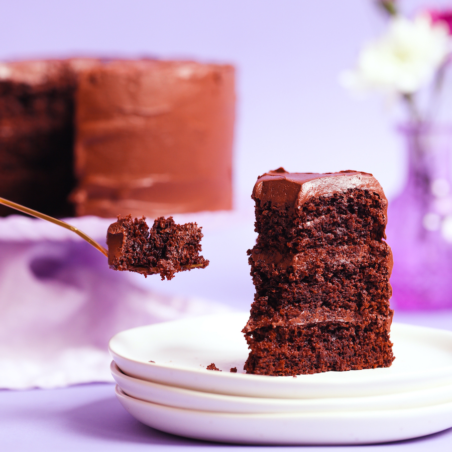 Bite of gluten-free chocolate cake on a fork next to a tall slice