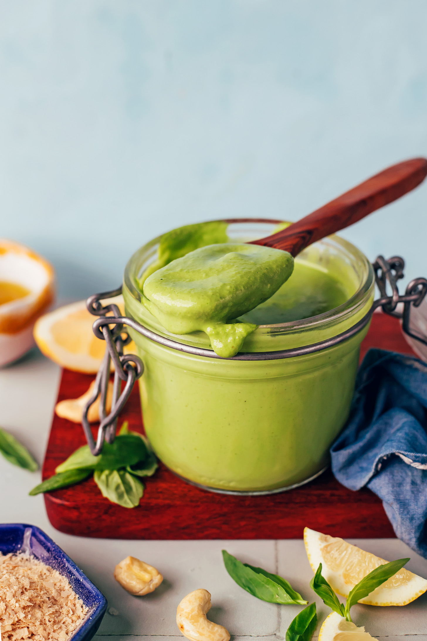 Wooden spoon full of creamy dairy-free pesto resting on a jar full of the pesto sauce recipe