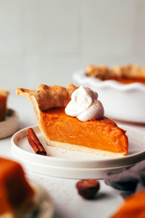 Slice of vegan sweet potato pie on a plate topped with cashew whipped cream