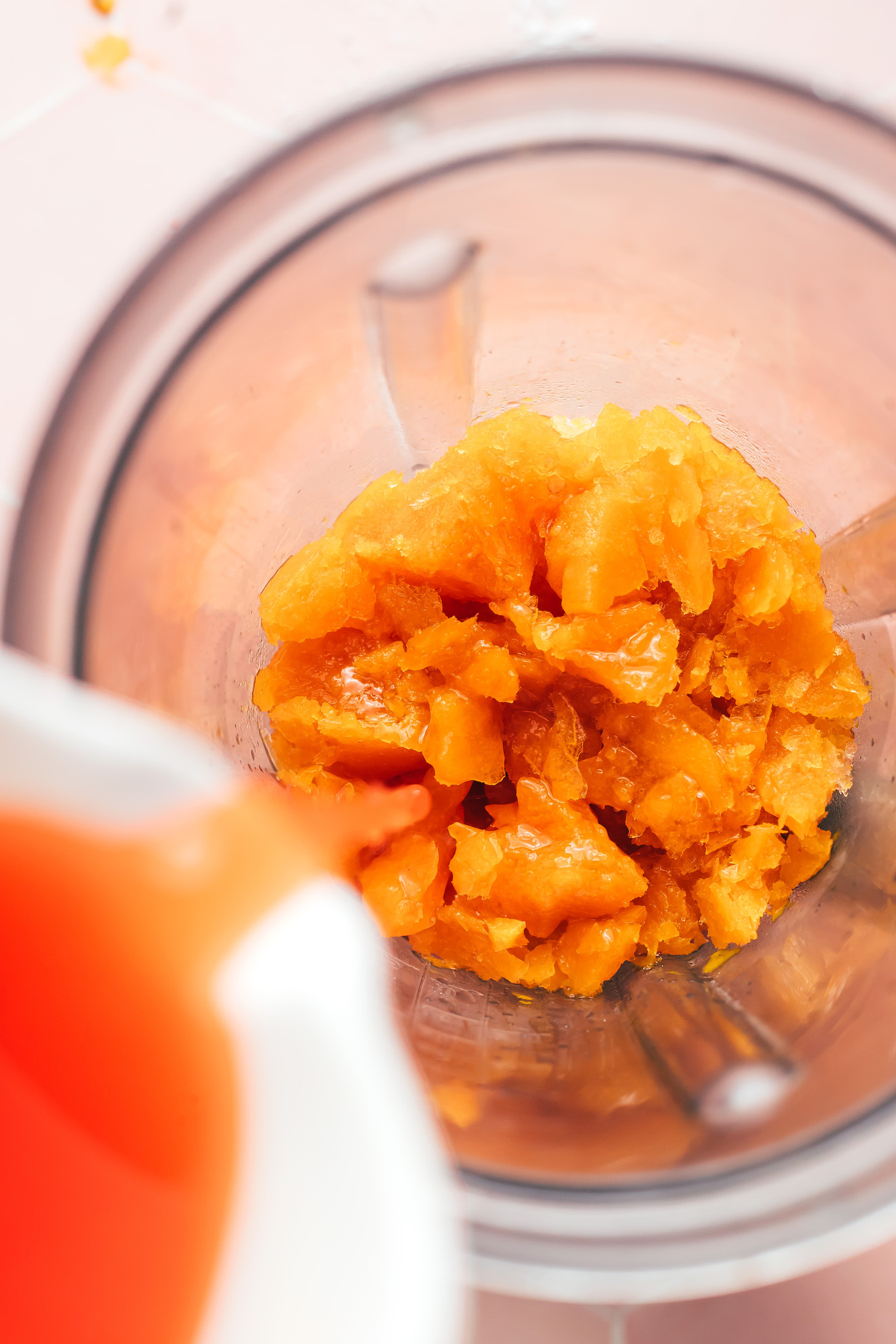 Pouring agave into a blender over frozen passion fruit