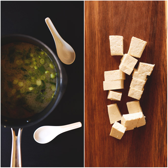 Sauce pan of miso broth and cubes of tofu on a cutting board