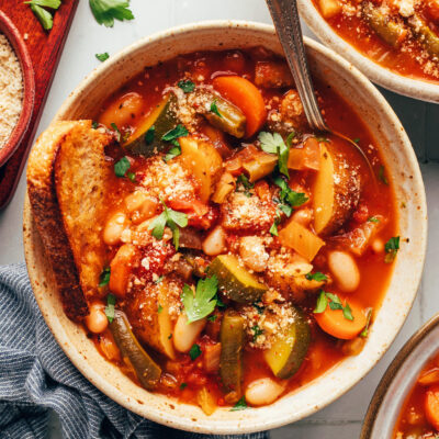 Bowl of white bean minestrone with a slice of bread in it