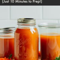 Jars of homemade vegetable broth on a cutting board