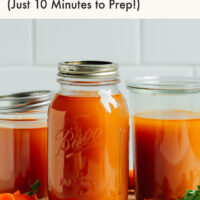 Jars of homemade vegetable broth on a cutting board