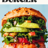 Close up photo of a salmon burger with toppings and text above it saying the ultimate salmon burger just 30 minutes