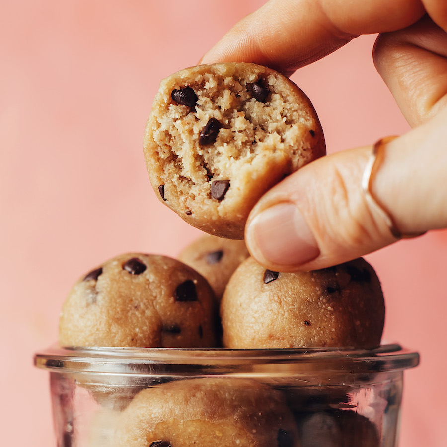 Fingers holding a edible chocolate chip cookie dough bite