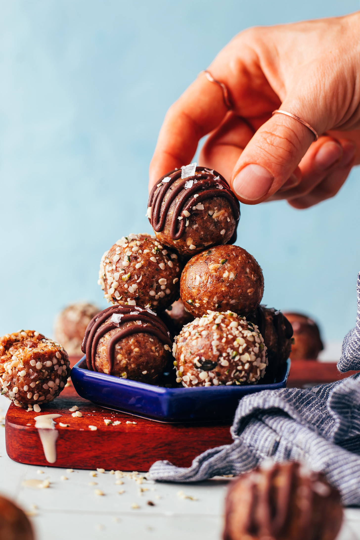 Picking up a seedy nut-free tahini snack bite from a stack with more bites