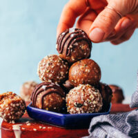 Picking up a seedy tahini snack bite covered with a chocolate drizzle