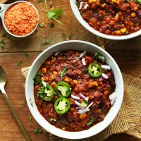 Big bowls of Red Lentil Chili garnished with sliced jalapeno, cilantro, and red onion