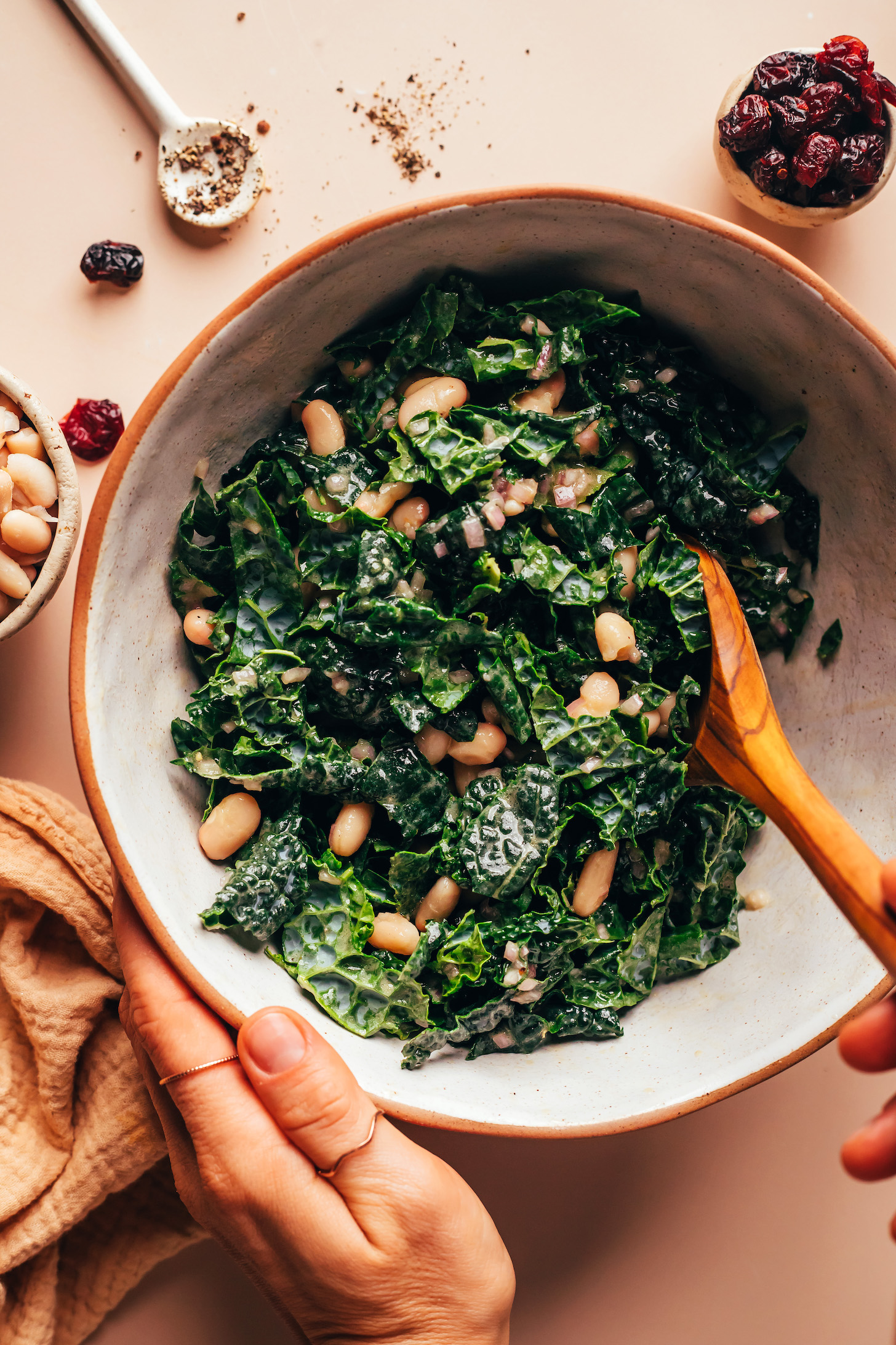 Stirring white beans and kale in a mixing bowl