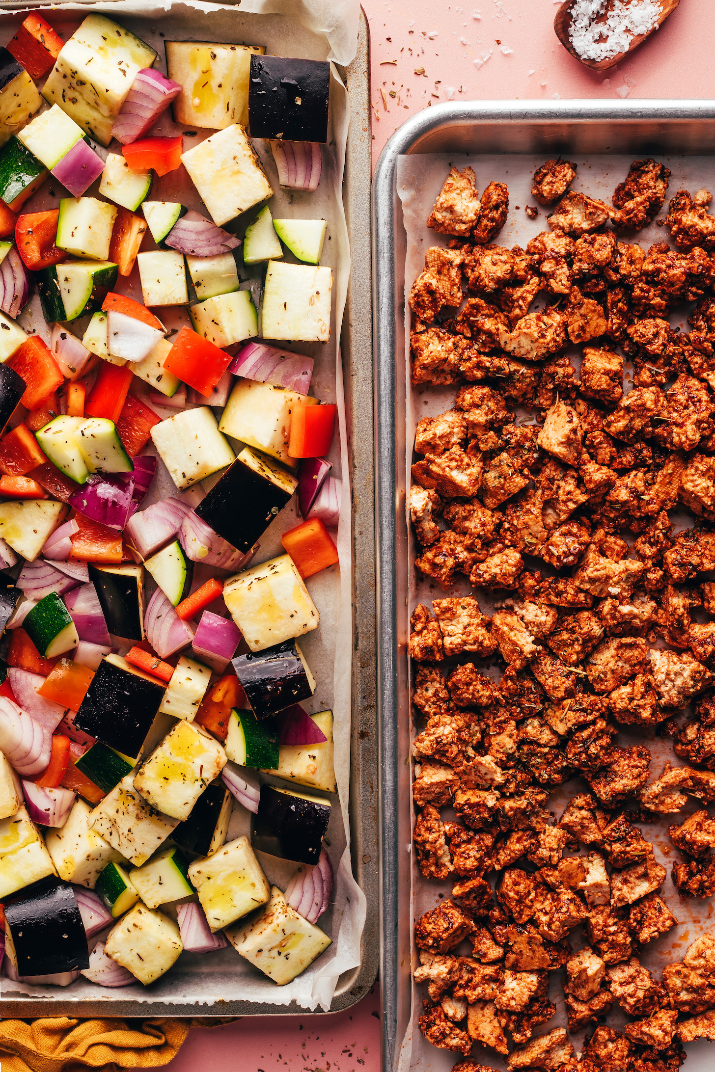 Two sheet pans, one containing crumbled tofu and the other with eggplant, bell pepper, zucchini, and red onion