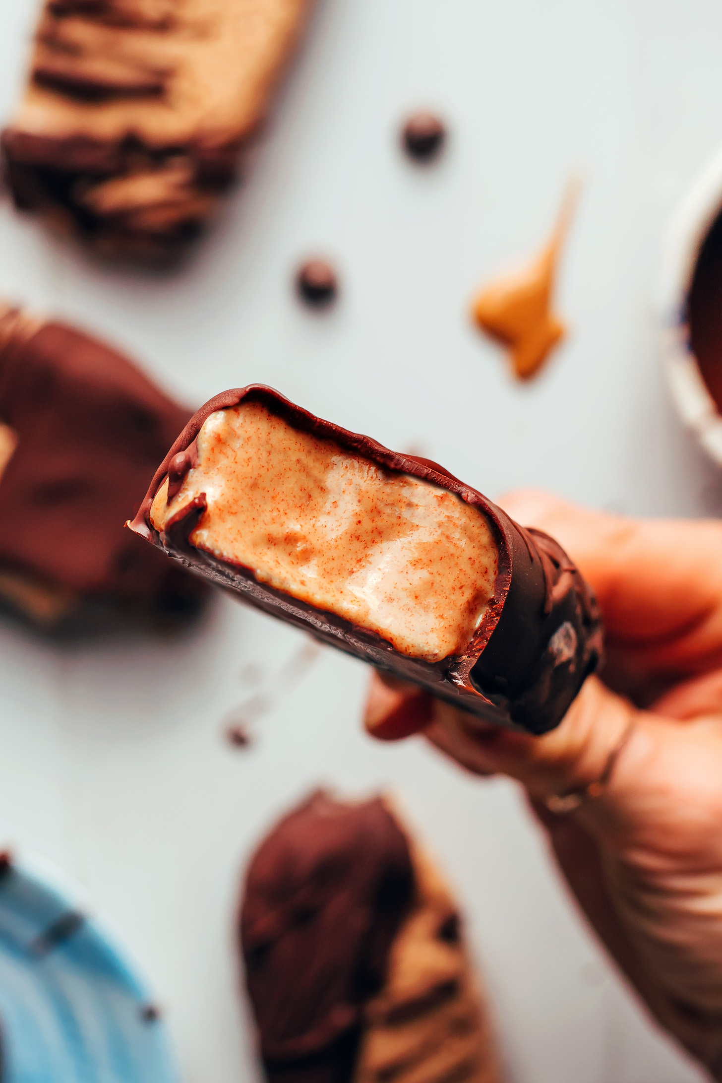 Close up photo of holding a creamy vegan peanut butter ice cream bar coated in chocolate