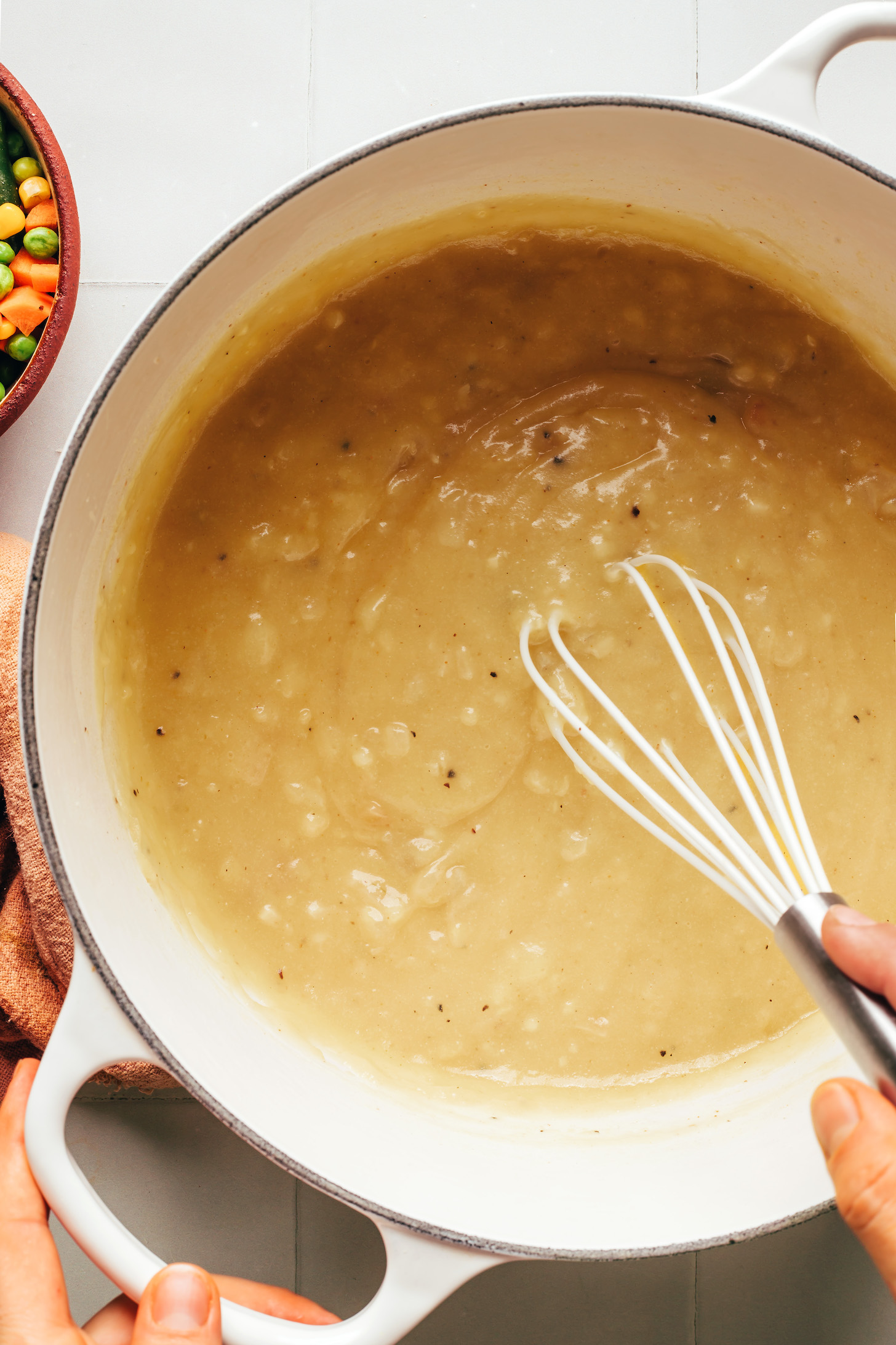 Whisking a bubbly mixture of sautéed onion, garlic, flour, salt, pepper, and vegetable broth